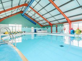 An indoor swimming pool with a blue floor and metal ladder at Beachcomber's Base - Hayling Island in Hayling Island Holiday Park