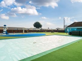 An outdoor swimming pool covered with a protective cover next to a children's play pool with a lighthouse slide at Beachcomber's Base - Hayling Island Holiday Park