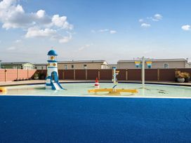 An outdoor shallow water play area with a lighthouse slide and water features at Beachcomber's Base - Hayling Island in Hayling Island Holiday Park