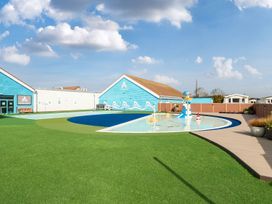 An outdoor area with a small pool and play equipment next to blue buildings at Beachcomber's Base - Hayling Island in Hayling Island Holiday Park