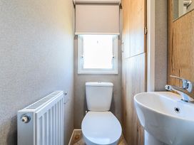 A small bathroom with a toilet sink radiator and window at Beachcomber's Base - Hayling Island Holiday Park