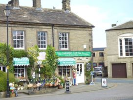The exterior of The Dalesman Cafe Tea Rooms with green awnings baskets and decorative items outside in Gargrave