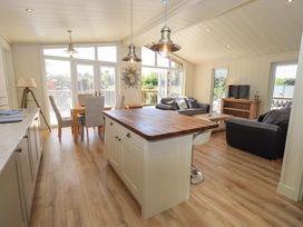 A combined kitchen and living room with a wooden island a dining table sofas and a television at Kingfisher Lodge in Gargrave