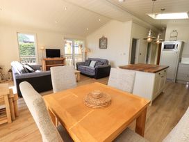 A living room and kitchen area with a wooden dining table and chairs a kitchen island and two sofas at Kingfisher Lodge in Gargrave