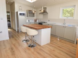 A kitchen with a wooden island countertop two white stools a microwave gas stove and window at Kingfisher Lodge in Gargrave