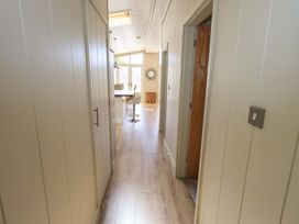 A hallway with wooden floor leading to a dining area with chairs and a mirror on the wall at Kingfisher Lodge in Gargrave