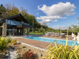 An outdoor area with a swimming pool and seating at Forest Lodge Pontyclun