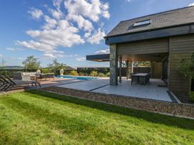 An outdoor area with a swimming pool and seating at Forest Lodge in Pontyclun