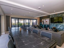 A dining room with a large table and sofa at Forest Lodge in Pontyclun