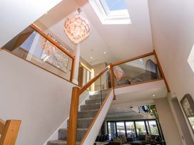 A staircase with a chandelier and glass railing at Forest Lodge in Pontyclun