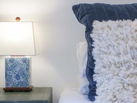 A bedside table with a lamp and decorative pillows at Forest Lodge Pontyclun