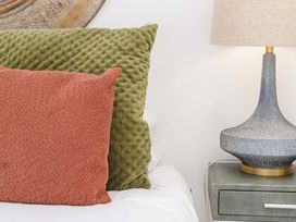 A bed with green and orange pillows and a lamp on a nightstand at Forest Lodge in Pontyclun