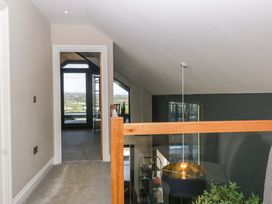 A hallway with a railing and light fixture at Forest Lodge in Pontyclun