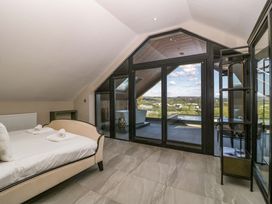 A bedroom with a bed and sliding doors overlooking the view at Forest Lodge in Pontyclun