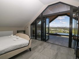 A bedroom with a bed and large windows at Forest Lodge in Pontyclun