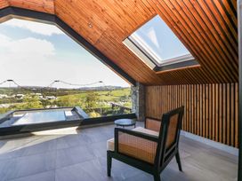 A room with a chair and table overlooking a pool at Forest Lodge Pontyclun