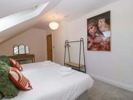 A bedroom with two beds, a shelf, and wall art at Forest Lodge in Pontyclun