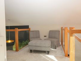 A loft area with armchairs and a footstool at Forest Lodge in Pontyclun