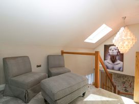 A loft area with chairs and an ottoman at Forest Lodge in Pontyclun