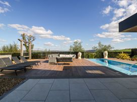 An outdoor patio with a pool and seating area at Forest Lodge in Pontyclun