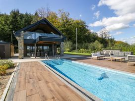 A swimming pool and house with seating area at Forest Lodge in Pontyclun