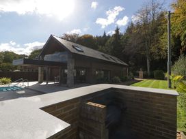 A modern building with a swimming pool and garden at Forest Lodge in Pontyclun