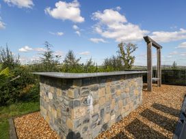 An outdoor area with a stone wall and swing at Forest Lodge in Pontyclun