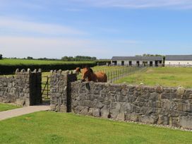 A farm with horses near a stone wall and barn at The East Wing Apartment Claremorris