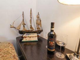 A living room with a model ship, wine bottle, wine glass and books at Rigg Cottage in Sandsend