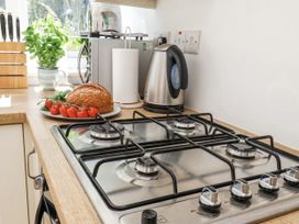 A kitchen with a gas stove and a plate of bread and tomatoes at Rigg Cottage in Sandsend
