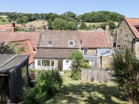 A garden view with rooftops and trees at Rigg Cottage Sandsend