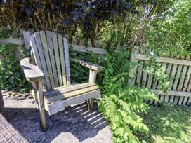 A wooden chair surrounded by ferns and a fence at Rigg Cottage in Sandsend