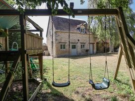 A swing set and playhouse in a garden at Stable cottage Sopworth near Sherston