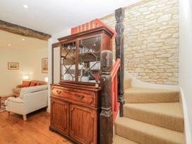 A living room with a wooden cabinet and staircase at Stable cottage Sopworth near Sherston