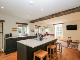 A kitchen with a kitchen island and bar stools at Stable cottage Sopworth near Sherston