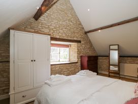 A bedroom with a bed and a wardrobe at Stable cottage Sopworth near Sherston