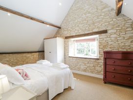 A bedroom with a bed and a wardrobe at Stable cottage Sopworth near Sherston