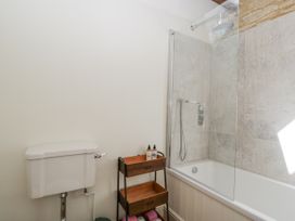 A bathroom with a bathtub and wall-mounted shower at Stable cottage in Sopworth near Sherston