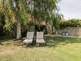 A garden with deck chairs and a stone wall at Stable cottage in Sopworth near Sherston