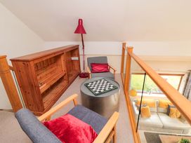 A loft area with a bookshelf, lamp, chairs, and a table at Lawnswood