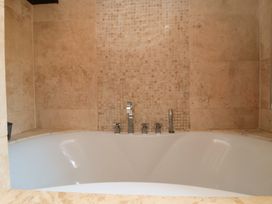 A bathtub with faucets and wall tiles at Lawnswood
