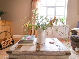 A living room with a coffee table displaying flowers and books at 11 Ballygate in Babbacombe