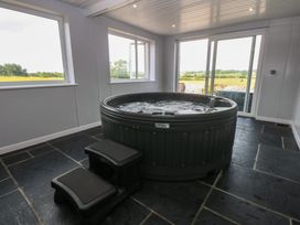 A hot tub in an indoor spa with windows at Morawelon in Pentraeth