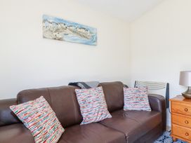 A brown leather sofa with three colorful patterned cushions in a living room with a wooden side table and lamp at 101 Atlantic Bays Holiday Park in Padstow