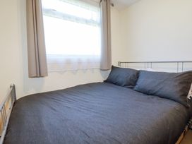 A bedroom with a metal bed frame gray bedding and a window with curtains at 101 Atlantic Bays Holiday Park in Padstow