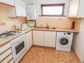A kitchen with a gas stove and washing machine at Flat 9 in Swanage
