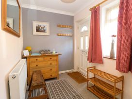 An entryway with a wooden chest of drawers a step stool a shoe rack and a door with a window at 3 Birkbeck Way in Norwich