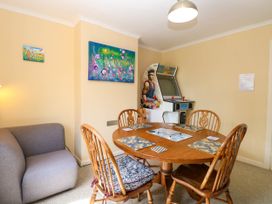 A dining area with wooden table and chairs a grey sofa and a vintage arcade game machine at 3 Birkbeck Way in Norwich