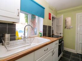 A kitchen with a sink a drying rack a stove and cabinets at 3 Birkbeck Way in Norwich
