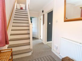 A hallway with carpeted stairs a radiator a mirror a wooden shoe rack and doors at 3 Birkbeck Way in Norwich